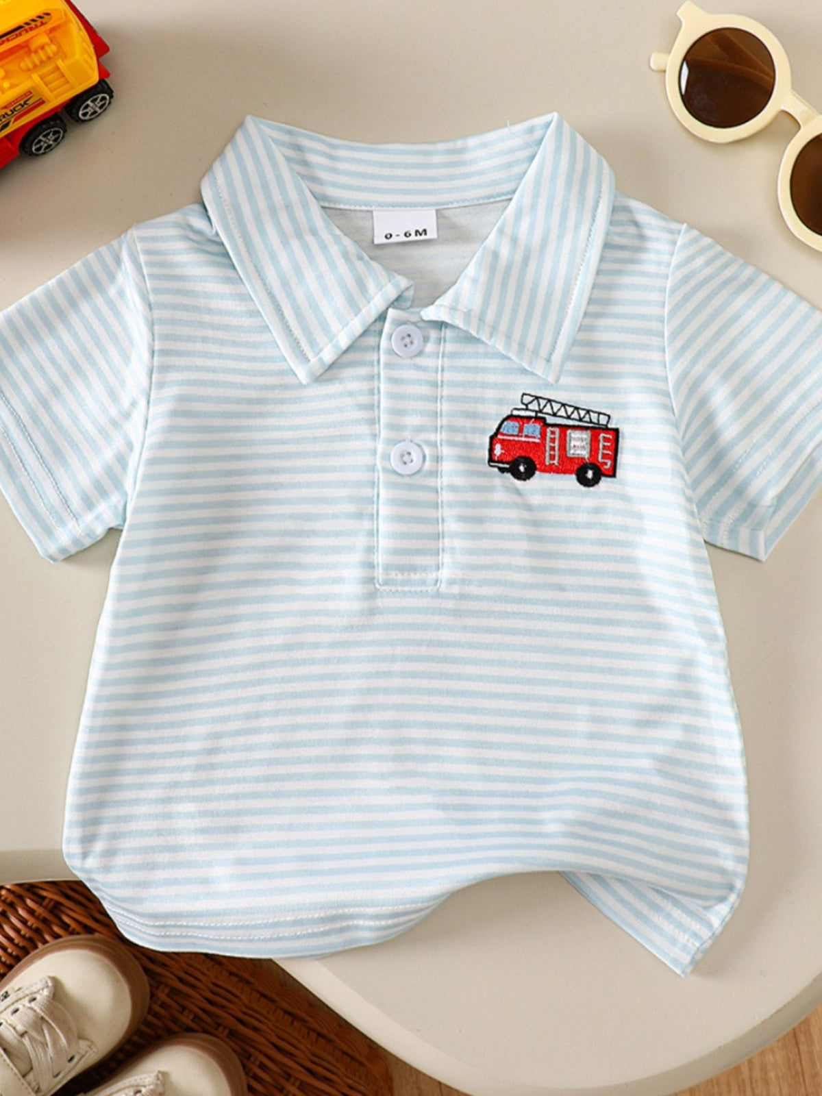 Baby polo shirt in blue and white stripes with a red firetruck embroidery.