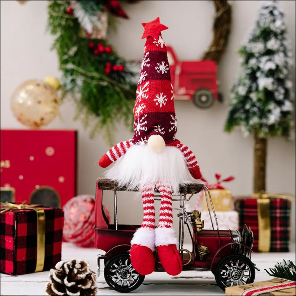 Illuminated knit gnome in red with snowflake pattern hat and striped legs sits on a red toy truck.