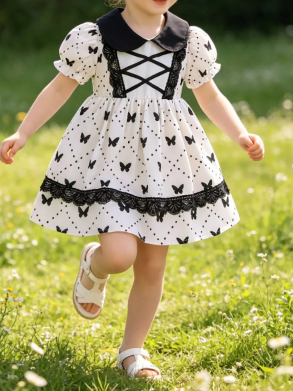 Baby dress with butterfly print, lace trim, puff sleeves, and black collar.