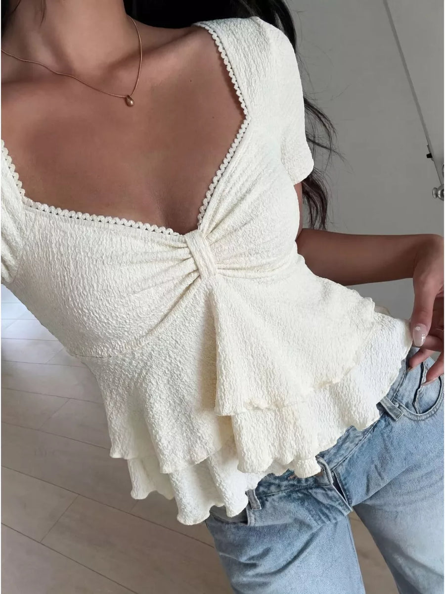 Cream textured peplum top with sweetheart neckline and ruffled tiers