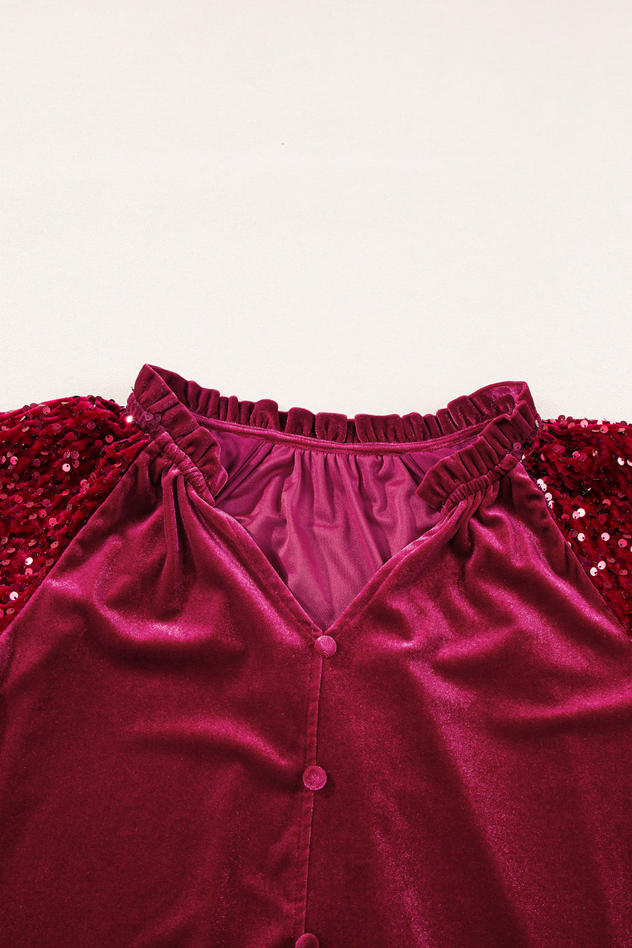 Red velvet blouse with sequin sleeves and ruffled neckline.