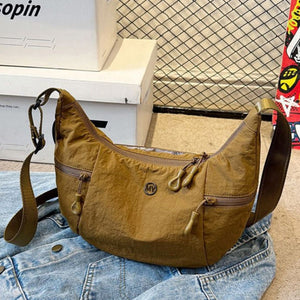 Medium brown nylon crossbody bag with adjustable strap and multiple zippered pockets.