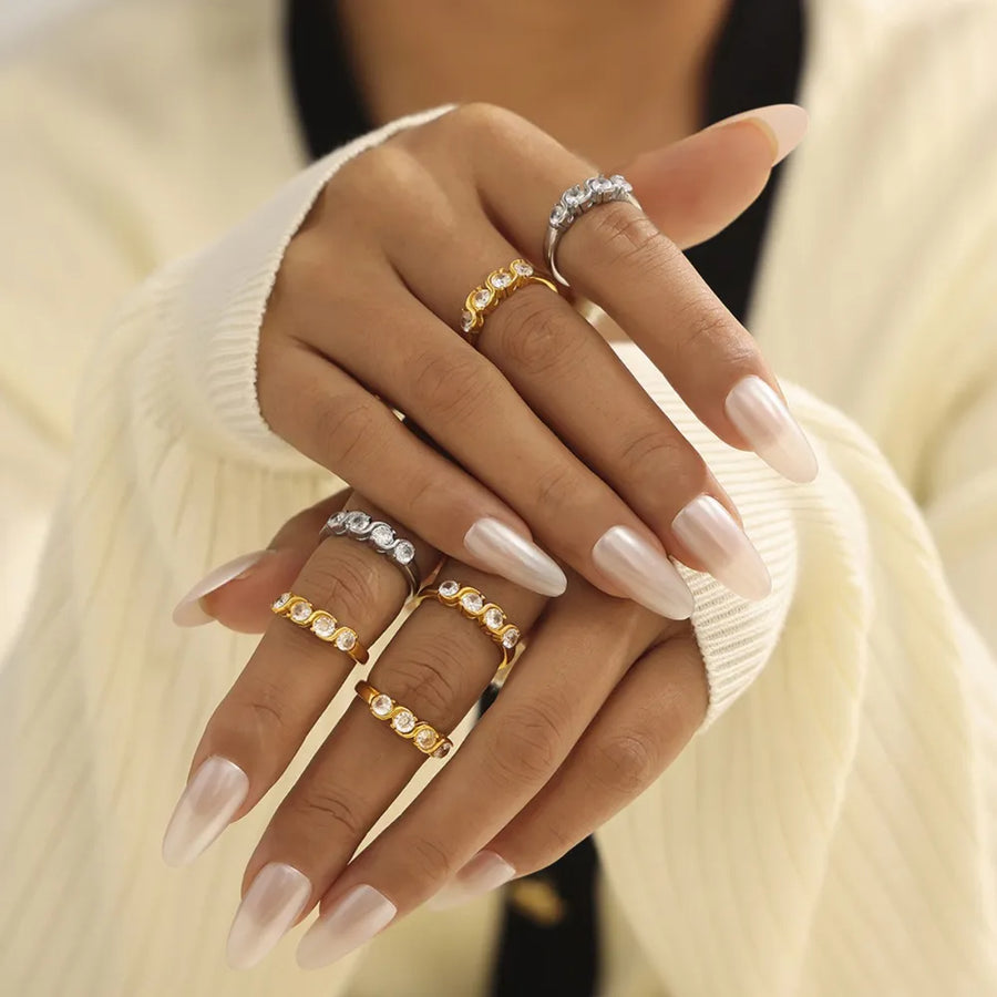 Gold and silver band rings with wave-set cubic zirconia stones.