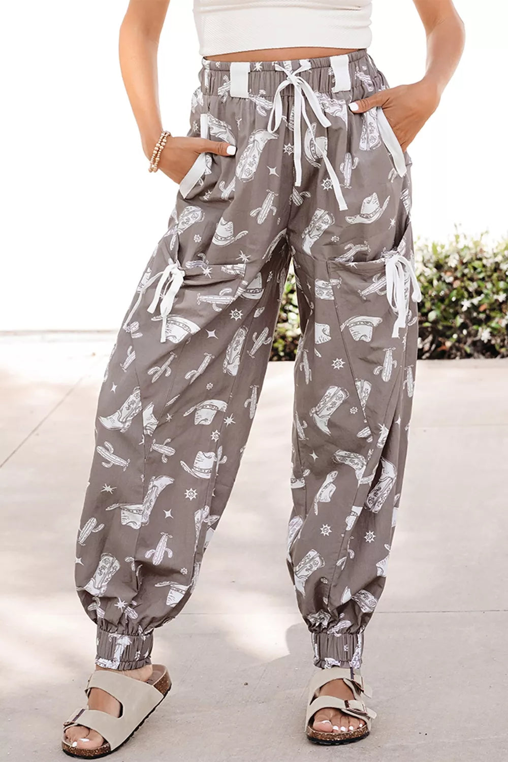 Grey cotton drawstring joggers with white western print, cuffed ankles, and cargo pockets.