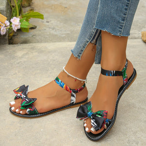 Floral bowknot flat sandals with colorful feather print straps and ankle strap.