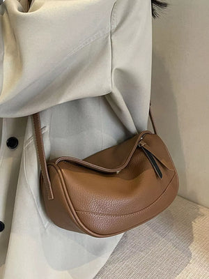 Brown pebbled leather crossbody bag with a curved shape and flap closure.