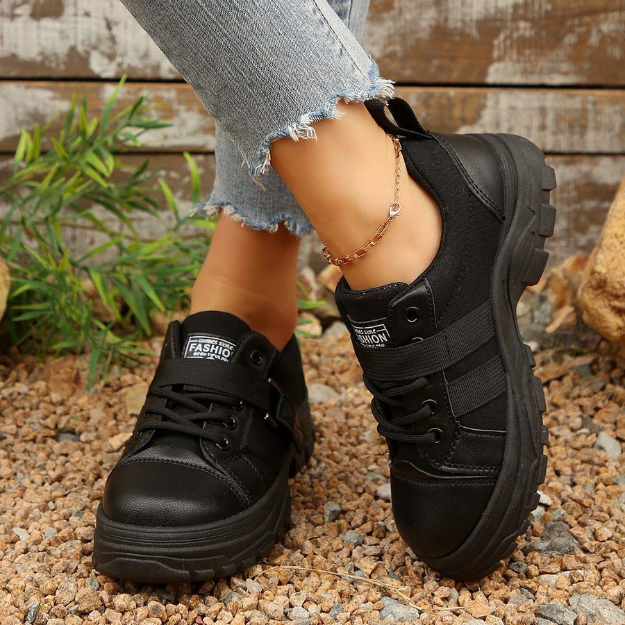 Black lace up platform sneakers with chunky soles and ankle strap detail.