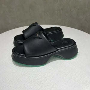 Black geometric platform slides with branding detail and green sole