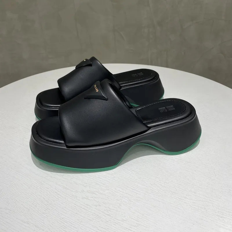 Black geometric platform slides with branding detail and green sole