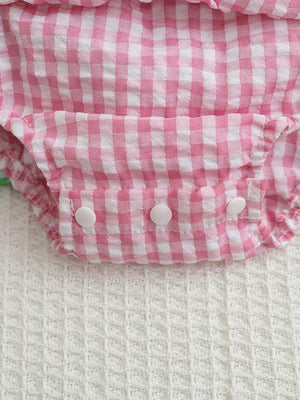 Pink gingham baby dress with smocked bodice and white button closures.