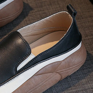 Black slip-on platform sneakers with white sole detail and textured brown sole.
