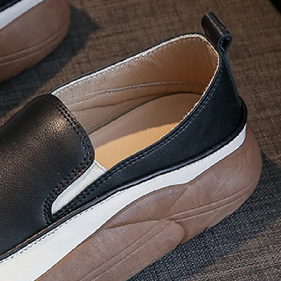 Black slip-on platform sneakers with white sole detail and textured brown sole.