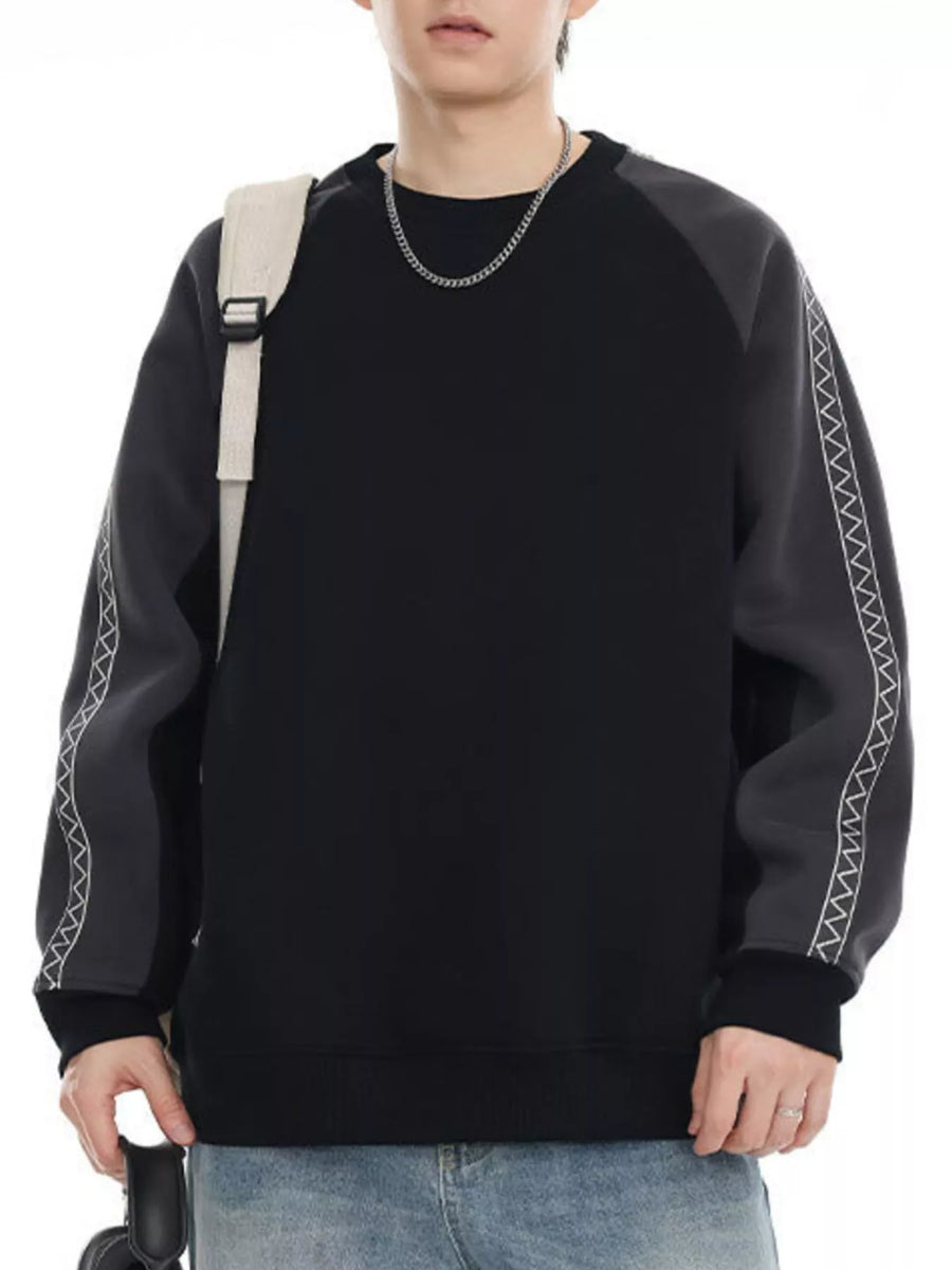 Black oversized raglan sweatshirt with contrasting gray sleeves featuring zigzag stitching detail.