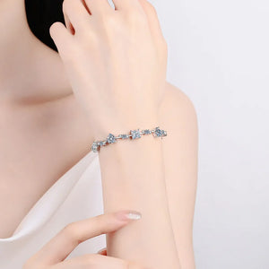 Silver geometric moissanite bracelet with assorted shapes and clear stones on a wrist.