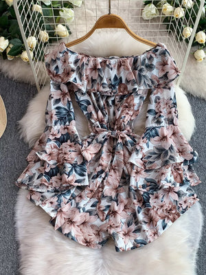 Off-shoulder ruffled romper with floral print, bow tie waist, and bell sleeves.