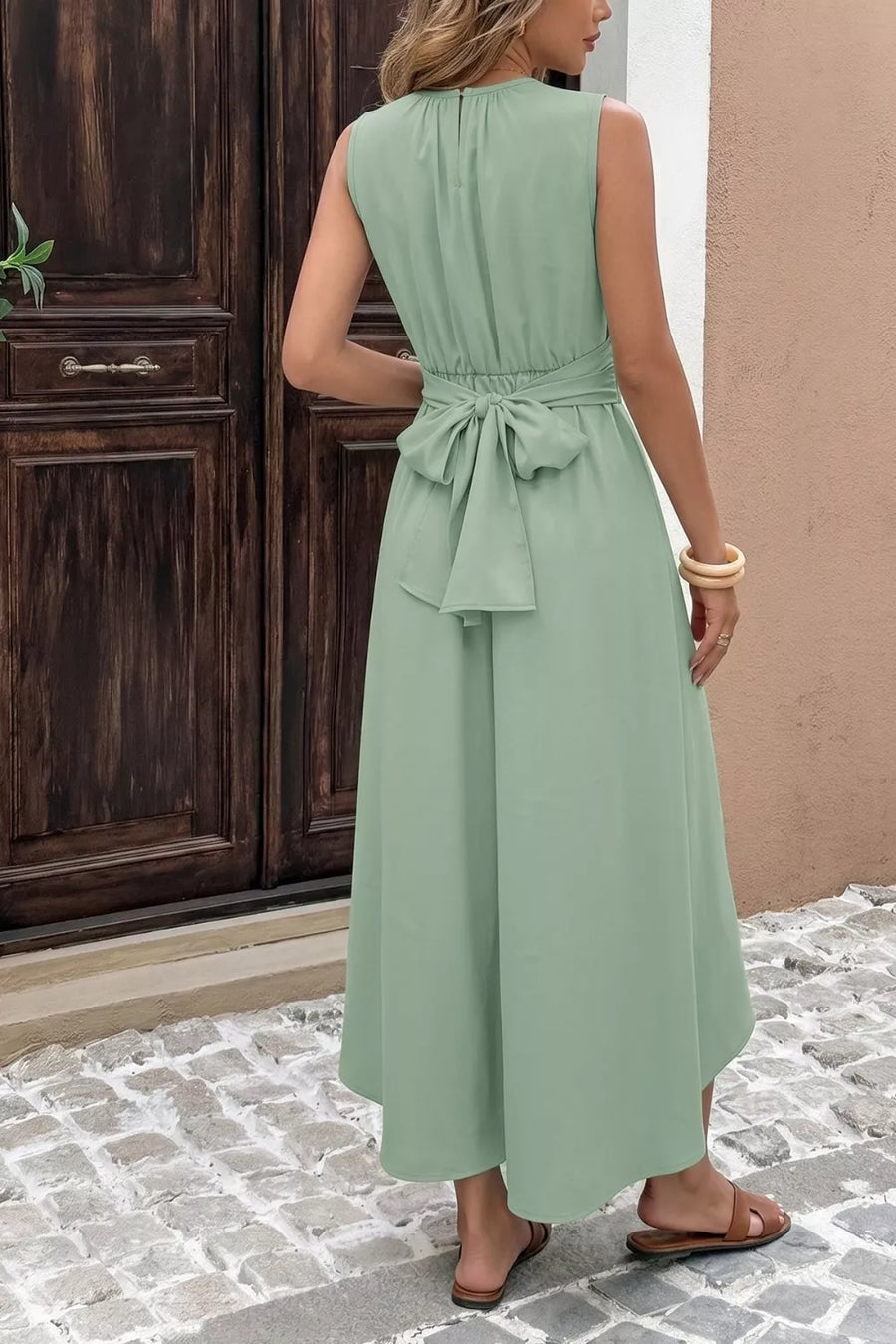 Sage green sleeveless high-low a-line dress with ruched waist and bow tie detail
