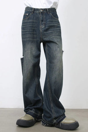 Baggy dark navy denim jeans with distressed knee slits and raw hems.