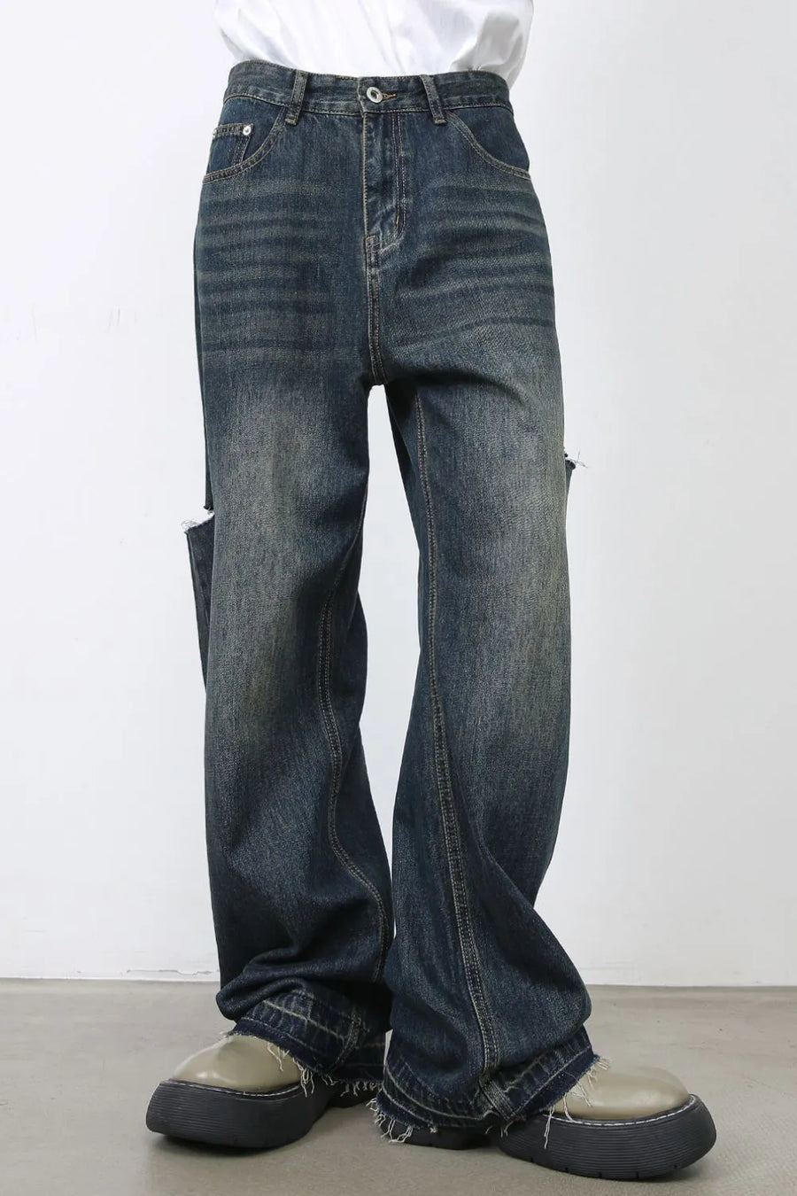 Baggy dark navy denim jeans with distressed knee slits and raw hems.