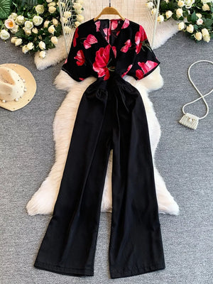 Black wide-leg romper with abstract floral print top and pockets.