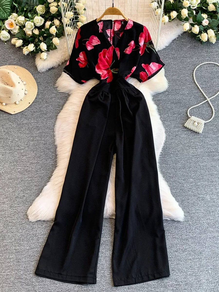 Black wide-leg romper with abstract floral print top and pockets.