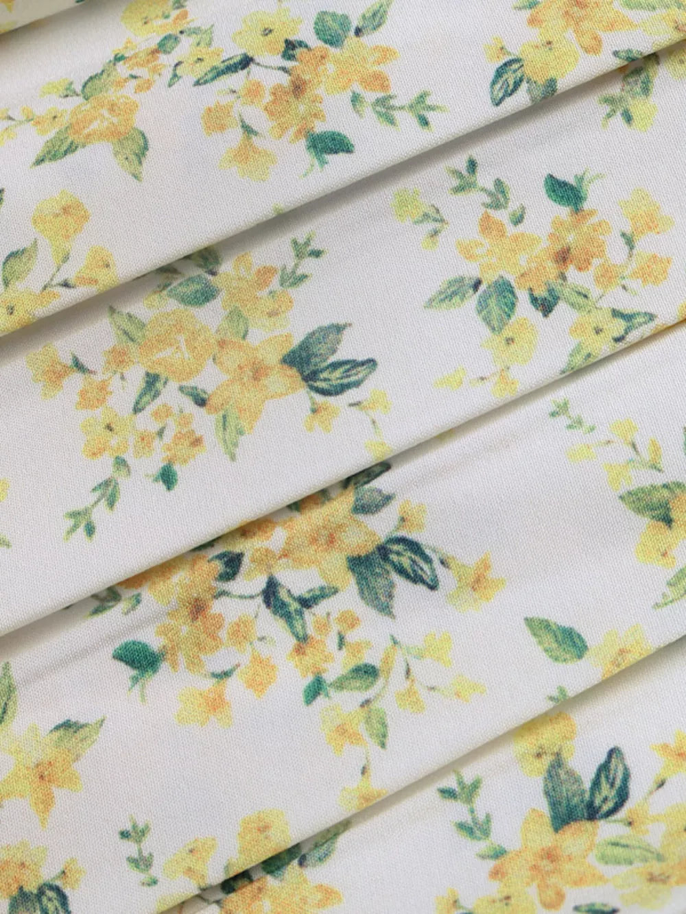 Charming floral mini dress fabric with yellow flowers and green leaves on white.