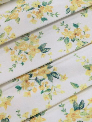 Charming floral mini dress fabric with yellow flowers and green leaves on white.