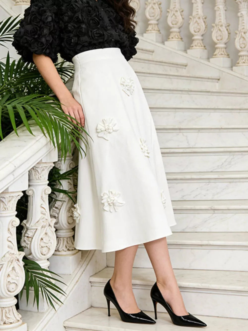 White midi skirt with 3D floral appliques and a black rosette puff-sleeve top