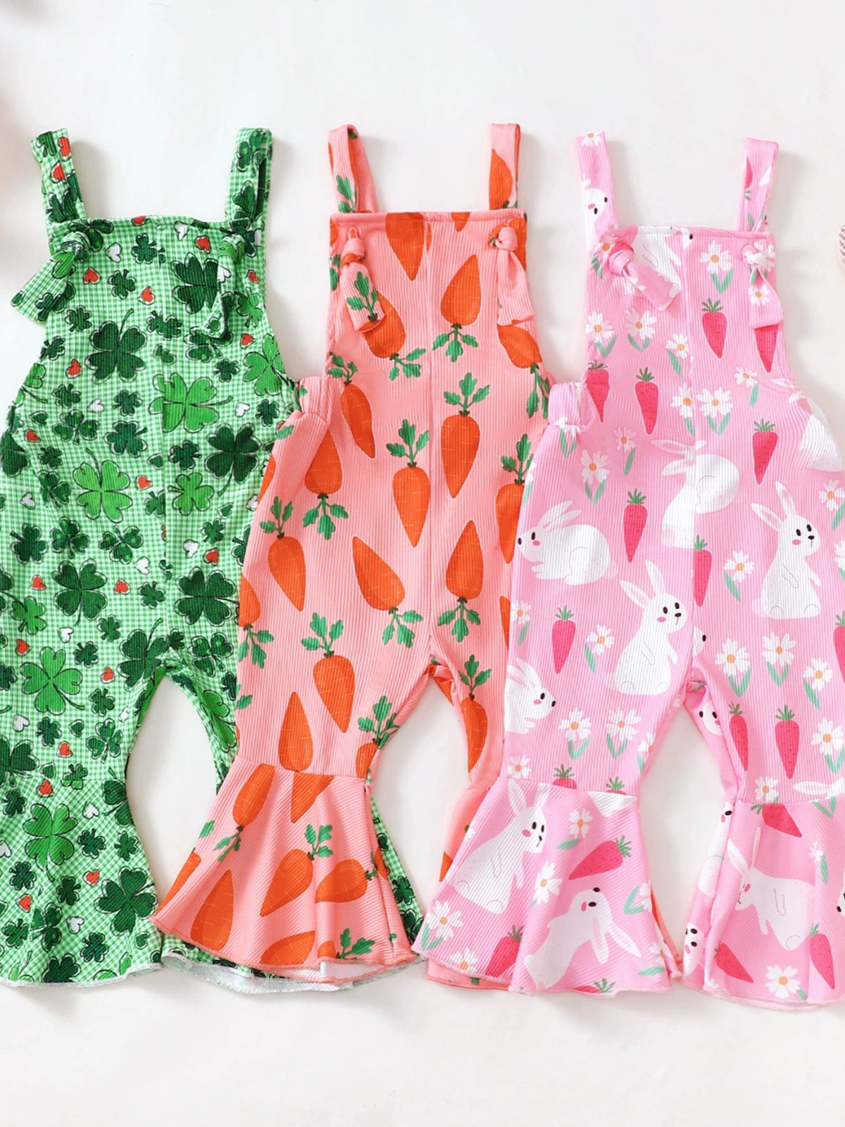 Baby overalls in green clover, pink carrot, and pink bunny prints with flare legs.