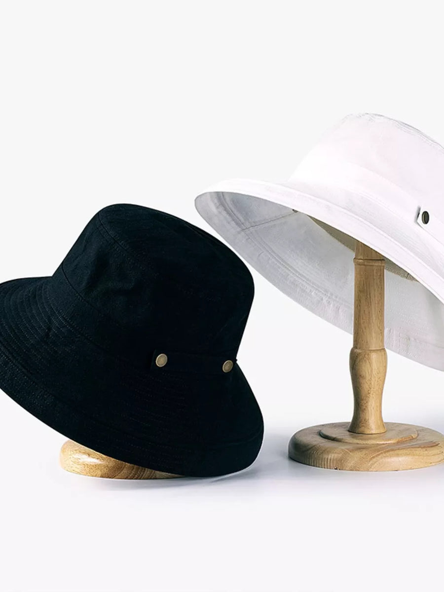 Black and white cotton bucket hats with brass hardware and wide brims.