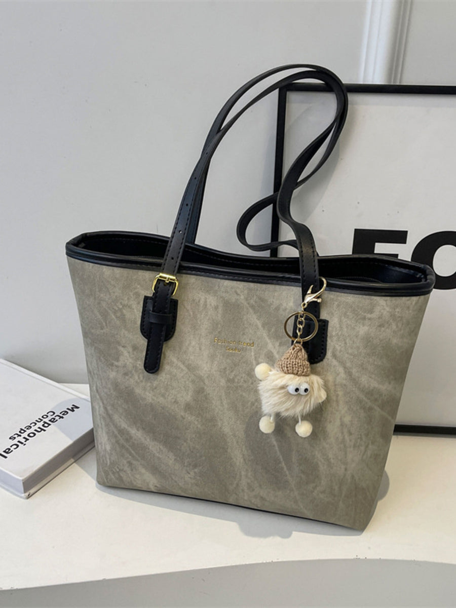 Distressed pu leather tote bag in dark gray with buckle accents and a fuzzy charm