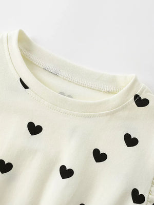 Children's cream dress with black heart print and ruffle sleeve detail.