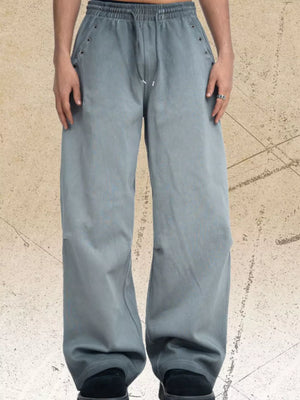 Men's grey wide-leg sweatpants with drawstring waist and grommet details.