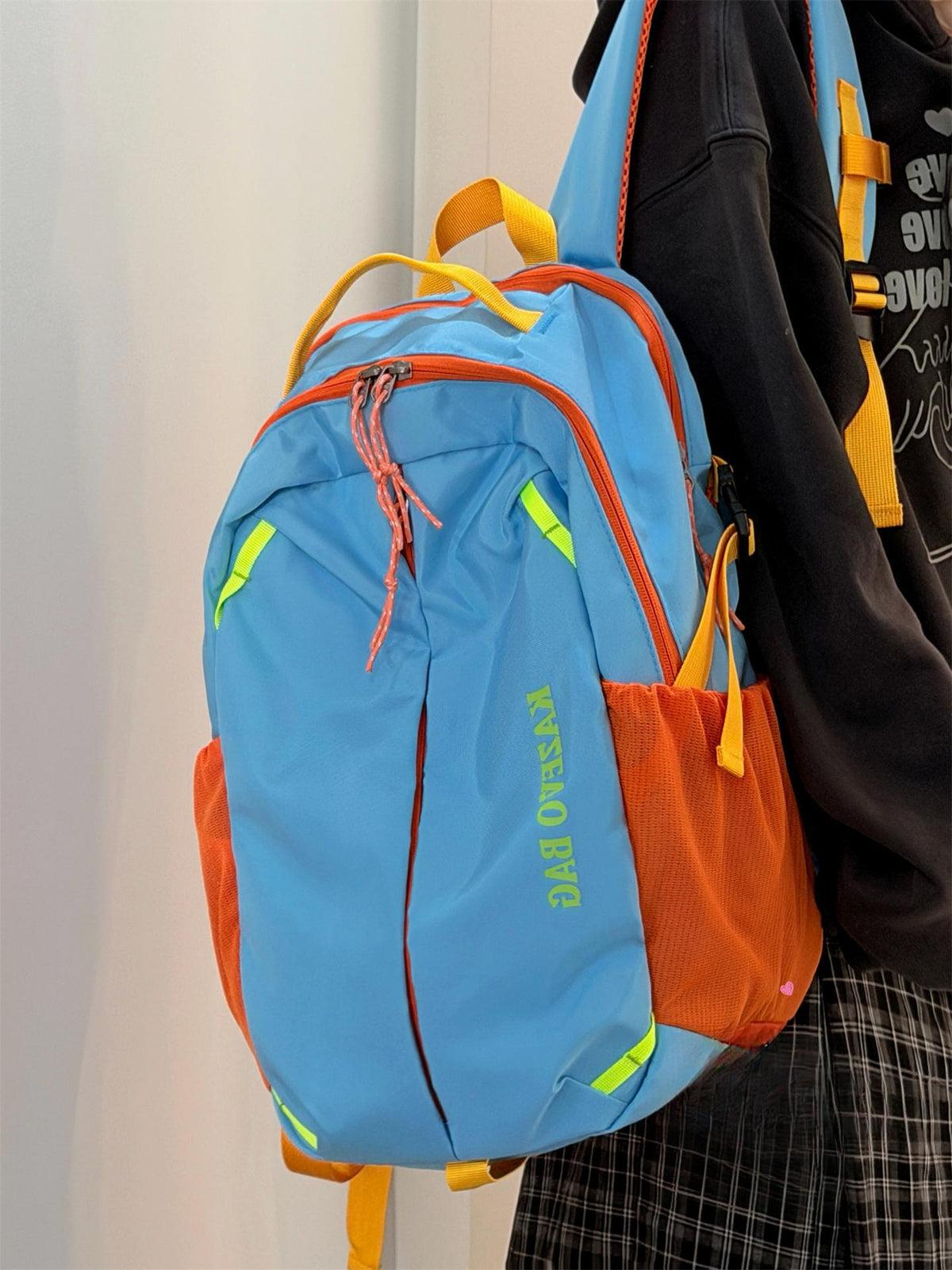 Medium blue nylon backpack with orange trim, yellow straps, and mesh side pockets.