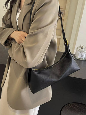 Black pebbled PU leather crossbody bag with gold zipper detail and adjustable strap.