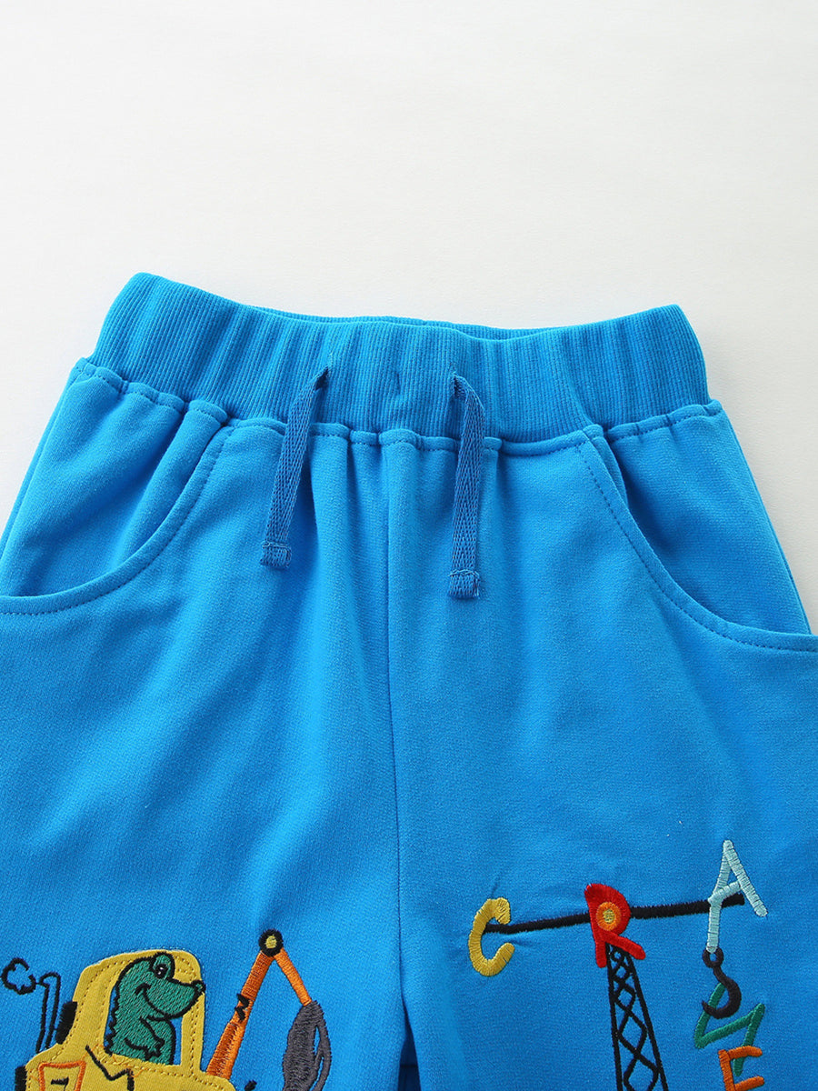 Blue cotton toddler boys' pants with embroidered construction vehicles and crane.