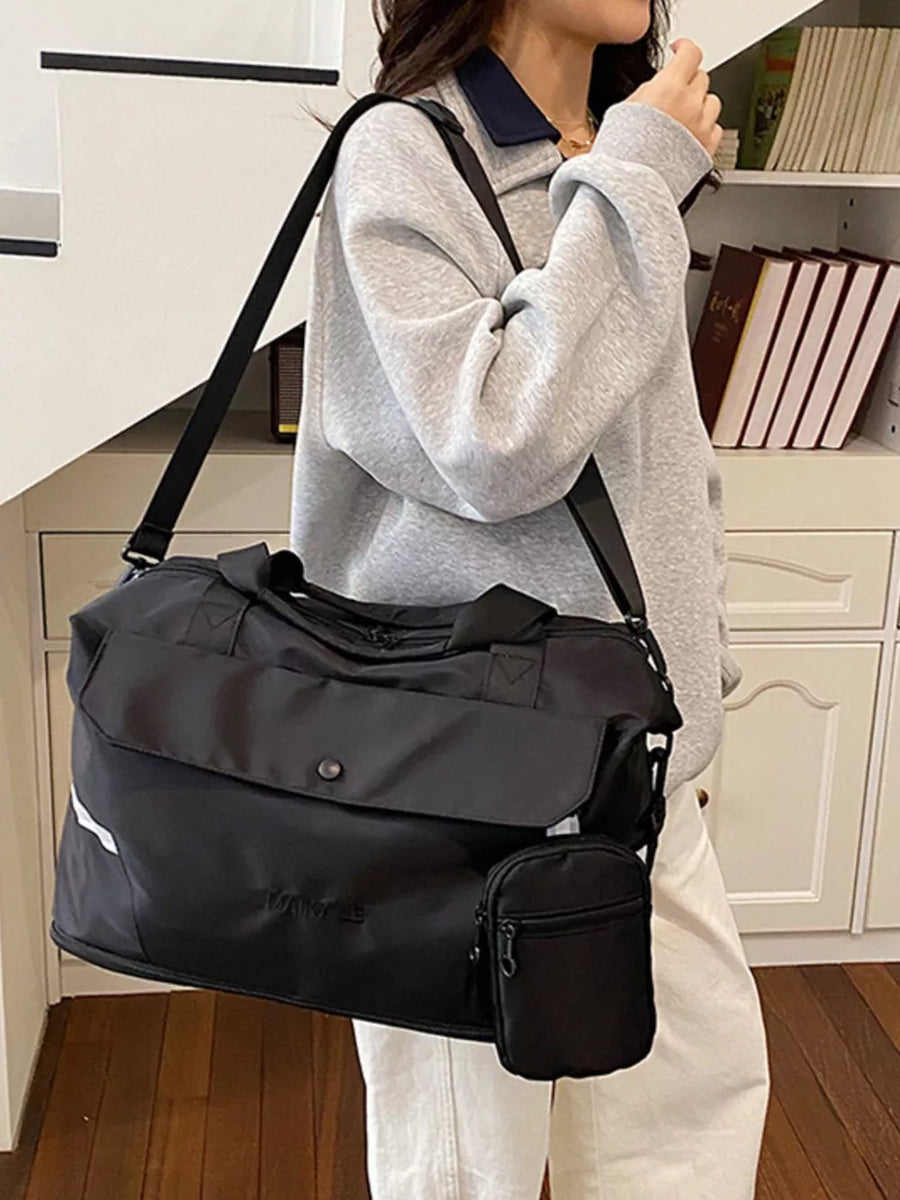 Black duffel bag with front flap, detachable pouch, and reflective stripe detail.