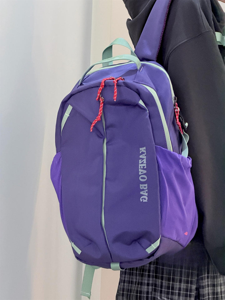 Purple nylon casual backpack with red rope zipper pulls and light green trim.