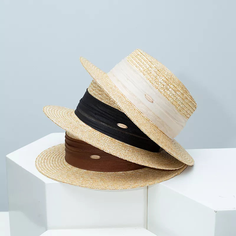 Refined straw boater hats in beige, brown, and black with ribbon detail.