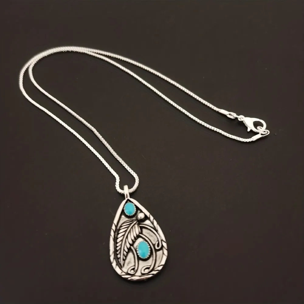 Silver pendant with turquoise stones and feather detail on a delicate chain.