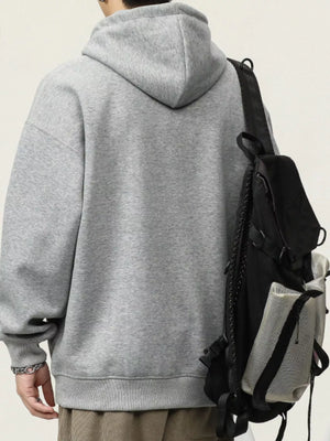 Gray cotton drawstring hoodie with a relaxed fit, worn with a backpack.