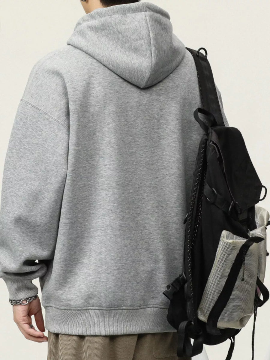 Gray cotton drawstring hoodie with a relaxed fit, worn with a backpack.