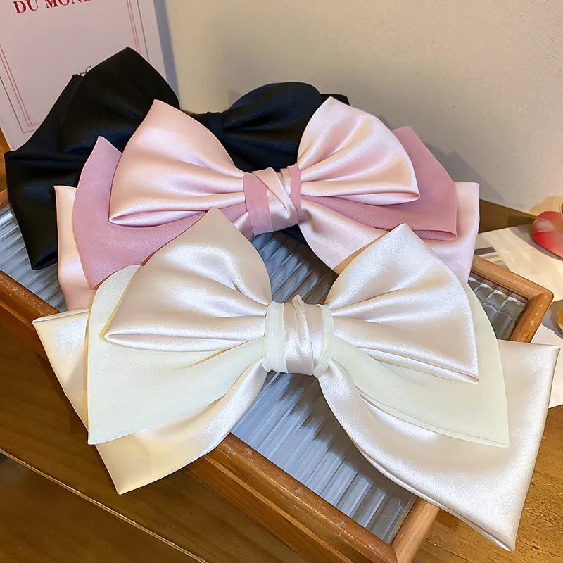 Satin bow barrettes in blush pink, black, and ivory with alloy details.