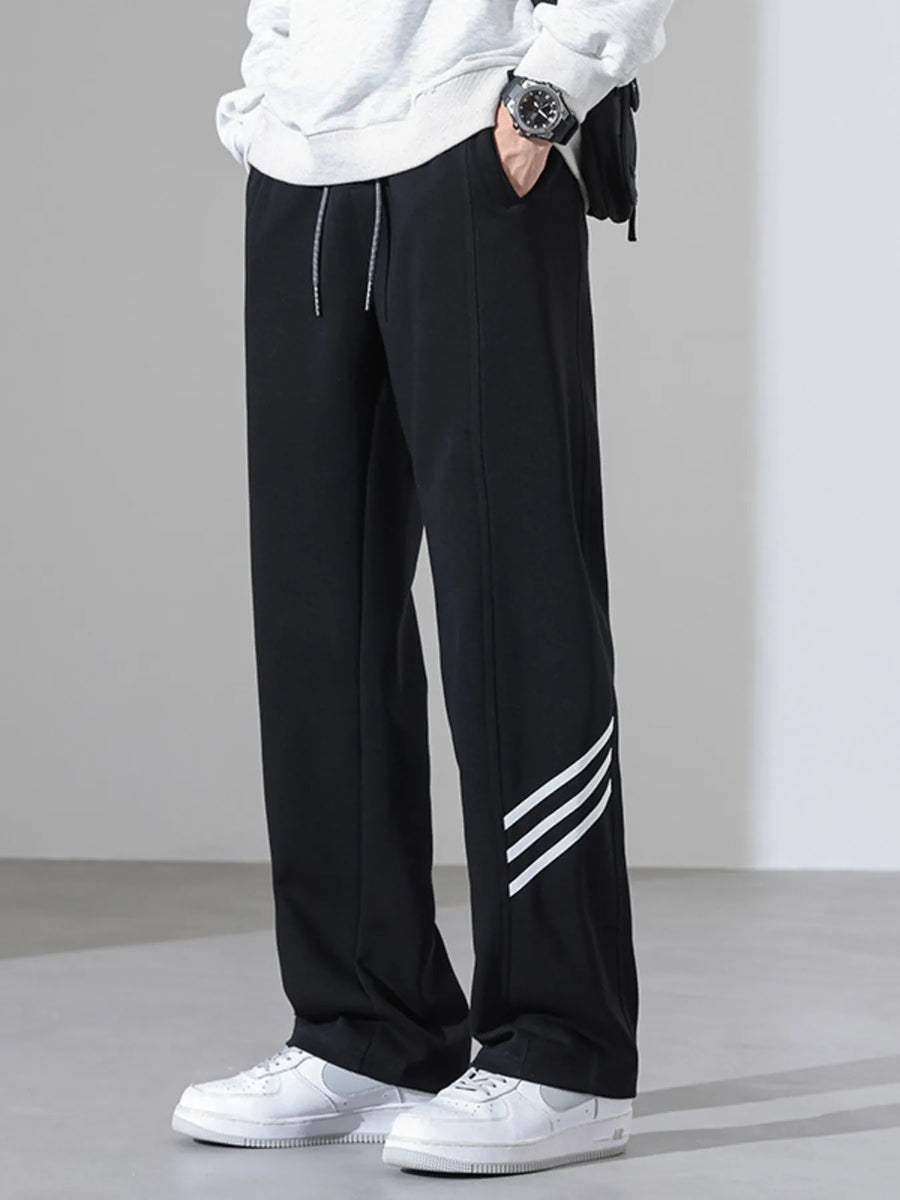 Black sweatpants with white side stripes and a drawstring waist.