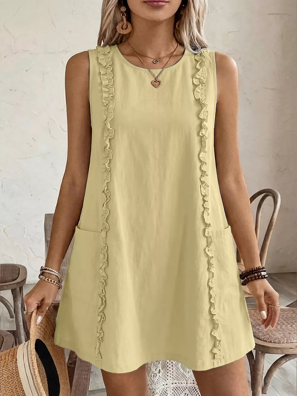 Pastel yellow sleeveless dress with frill details and pockets.