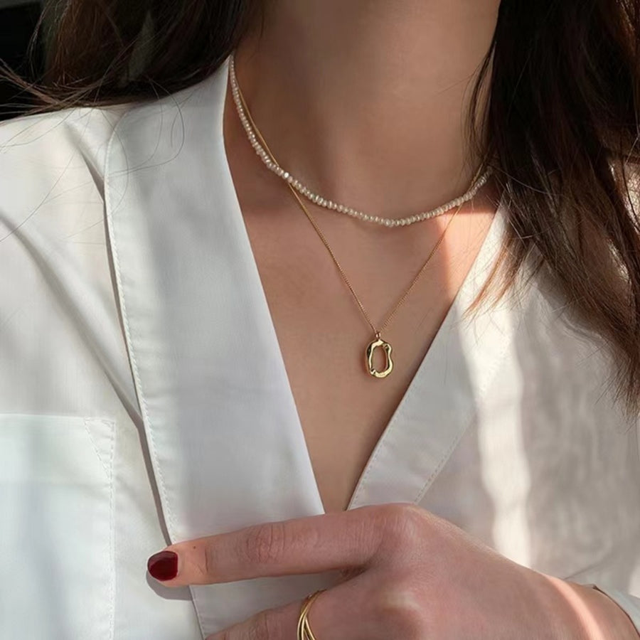 Gold geometric pendant necklace set with pearl strand necklace.