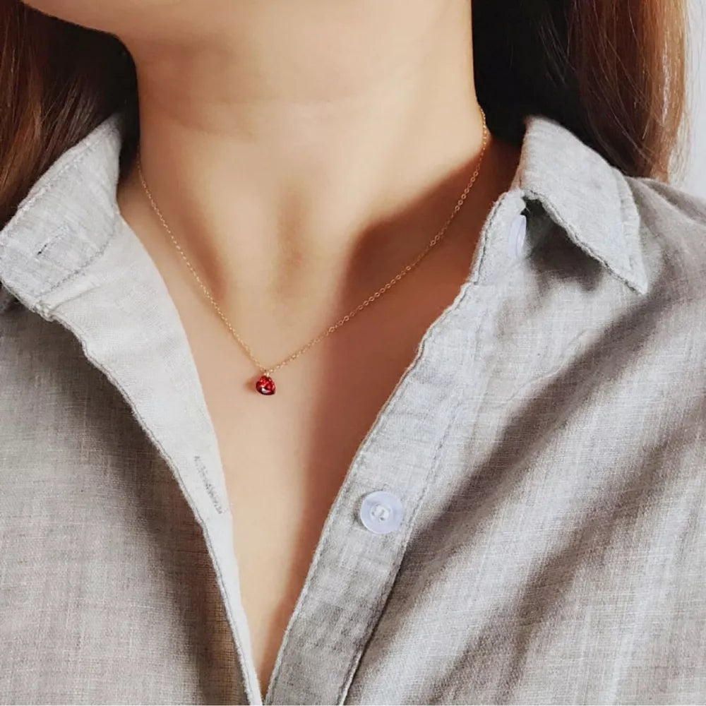 Gold delicate necklace with a small red heart zircon pendant.