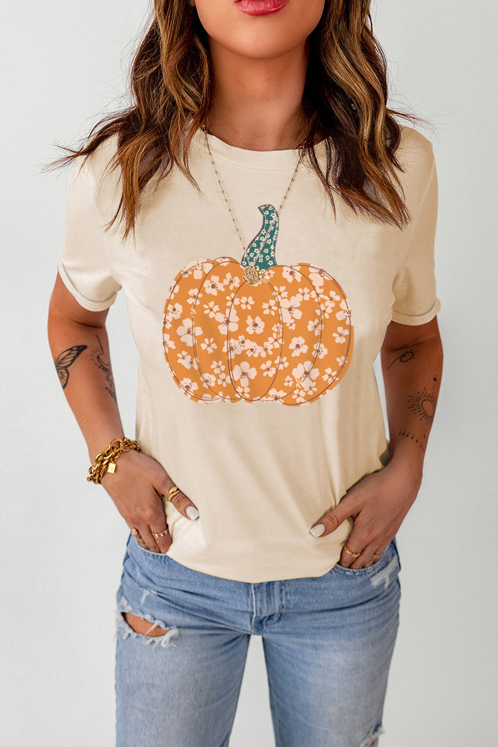Cream t-shirt with a floral pumpkin graphic and a teal stem.