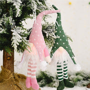 Knitted gnome ornaments in blush pink with heart pattern and green with heart pattern hang on a tree.