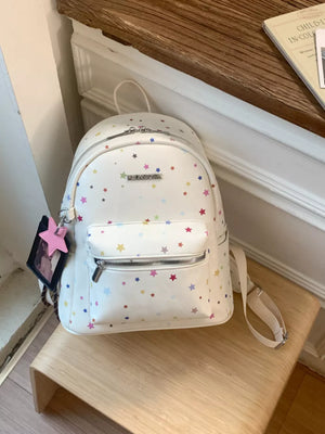 White mini backpack with colorful star print and front zip pocket.
