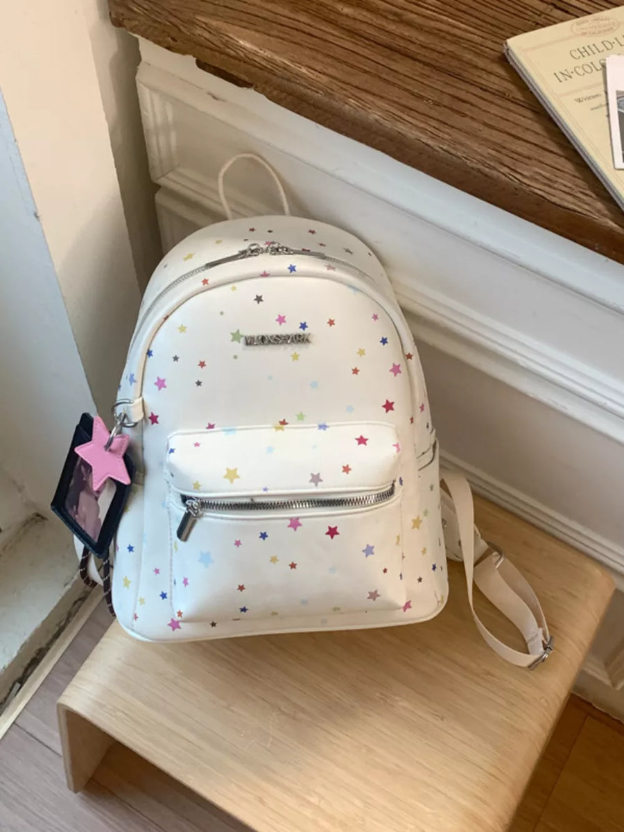 White mini backpack with colorful star print and front zip pocket.